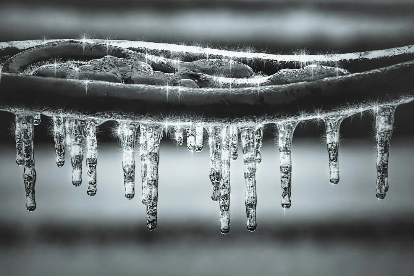Icicles hanging from a frozen pipe in winter