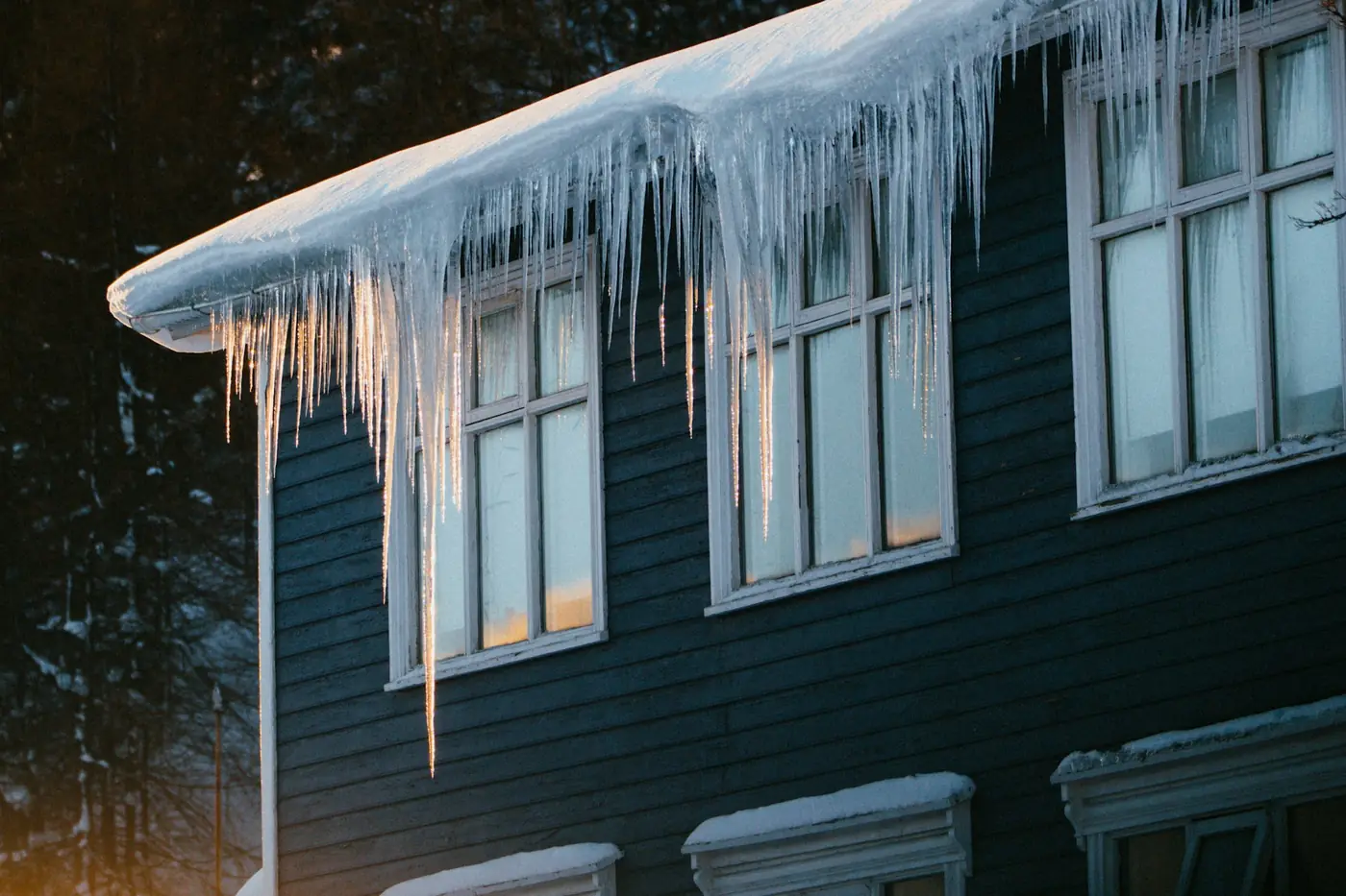 House with long icicles hanging from the roof on a cold winter evening