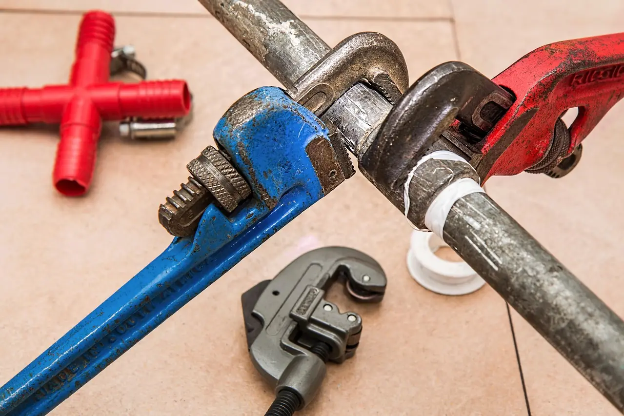 Pipe wrenches and plumbing tools set up for a pipe repair