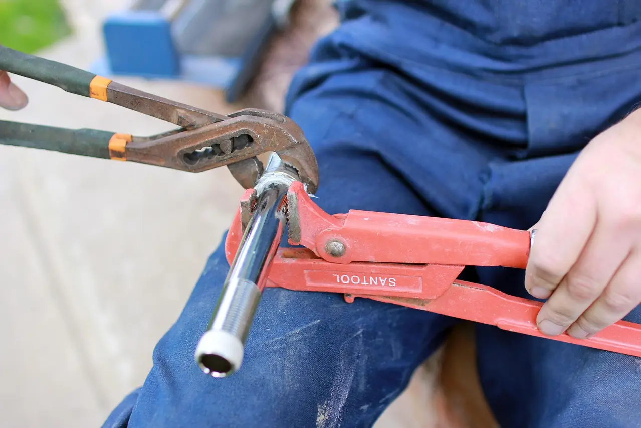 Plumber holding a pipe with two pipe wrenches while replacing a section of water line