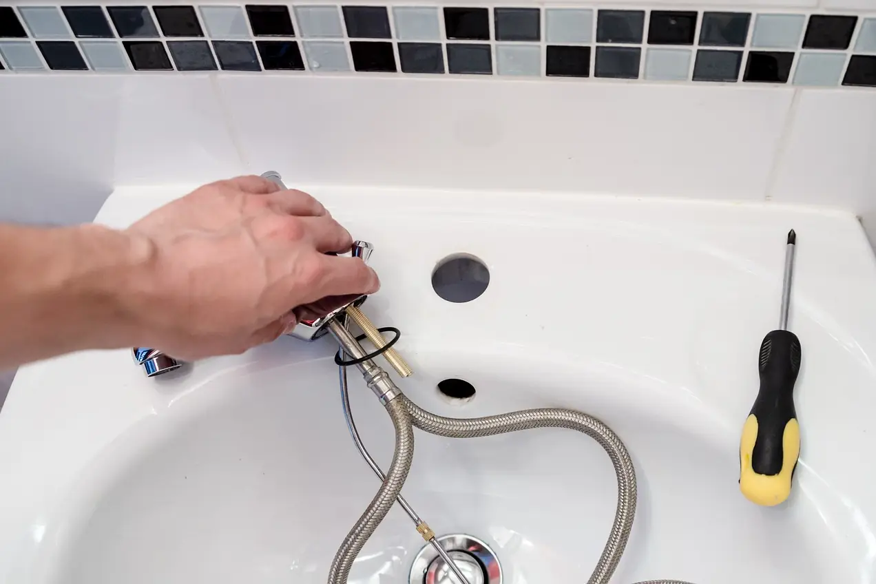 Plumber connecting the supply lines while installing a new bathroom faucet