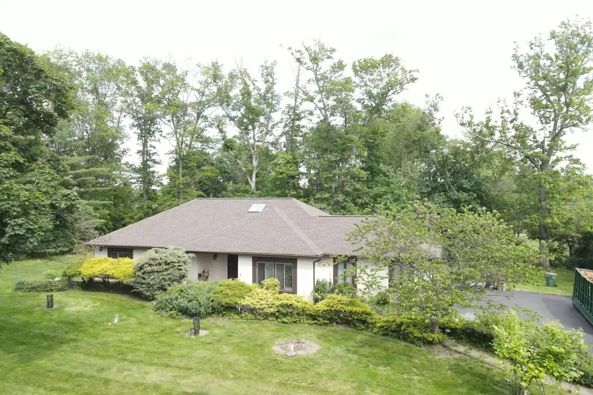 Ranch-style home on a green lawn with mature trees