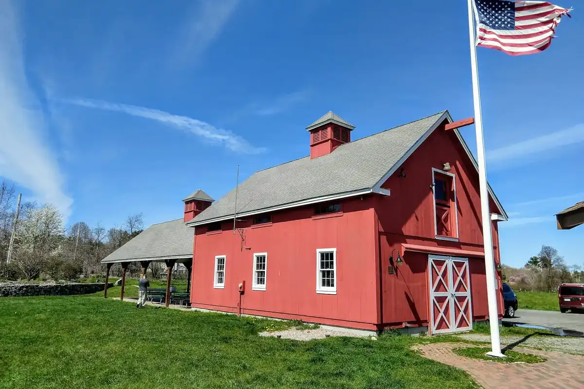 Red barn and flagpole on a green lawn under a blue sky