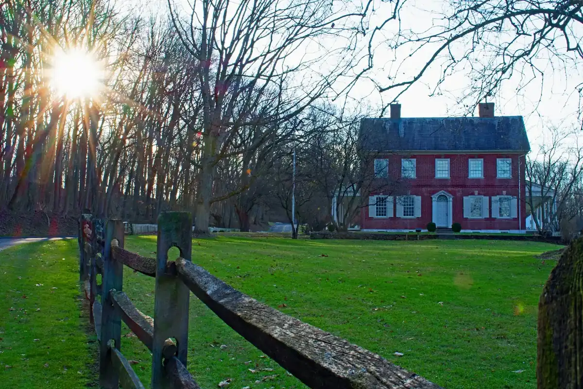 Red brick house behind a wooden fence on a sunny day