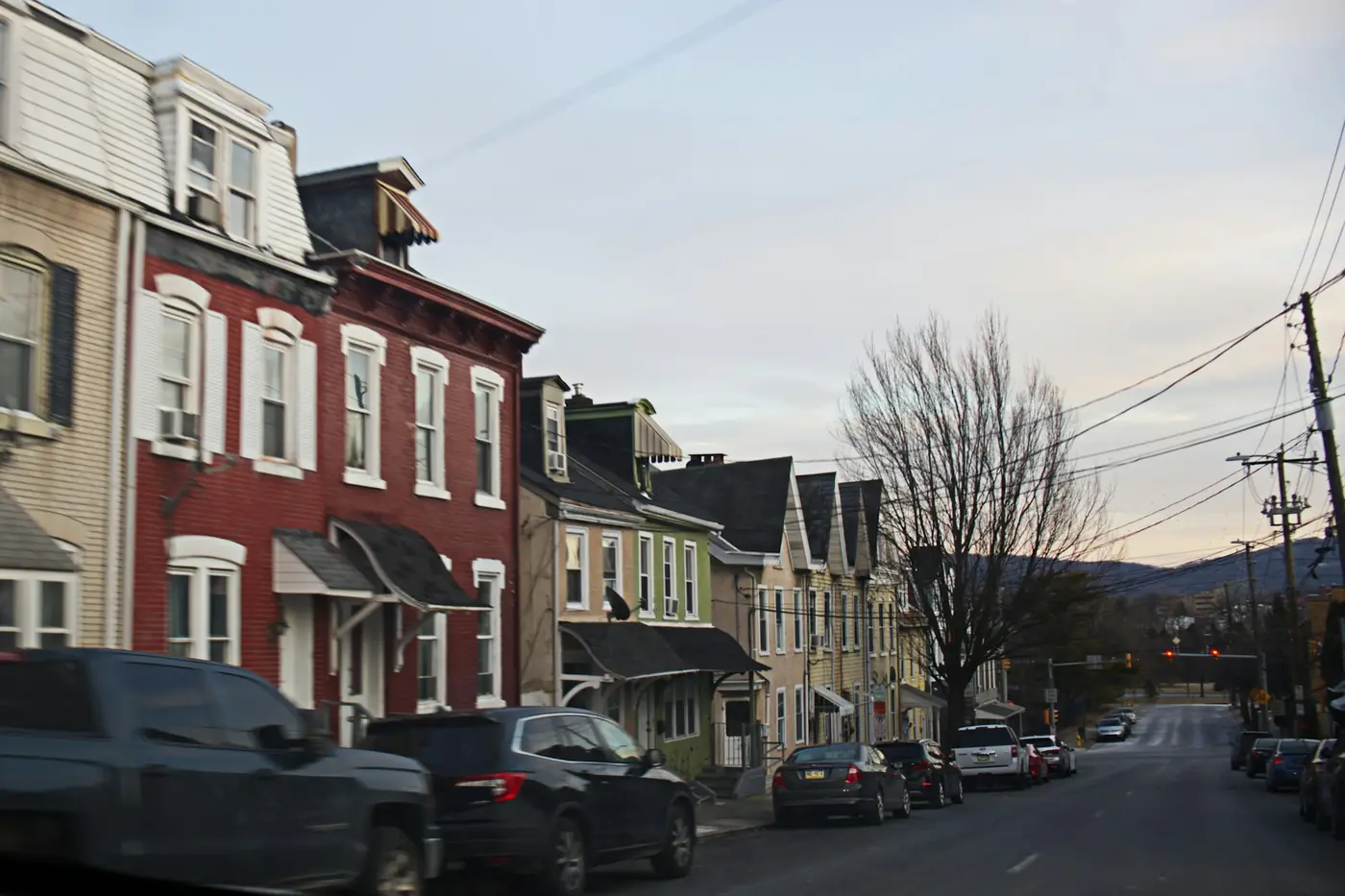 Street of older row homes with cars parked along the curb