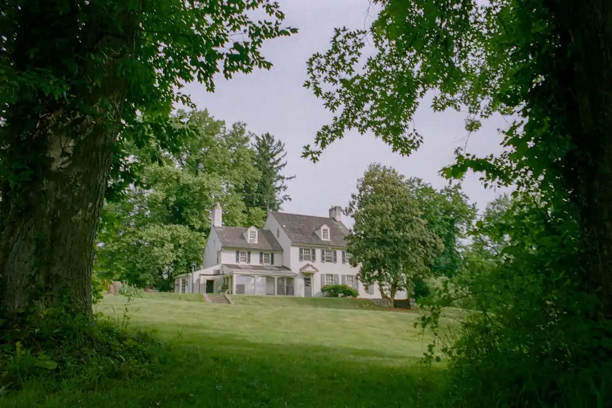 White two-story house surrounded by tall trees