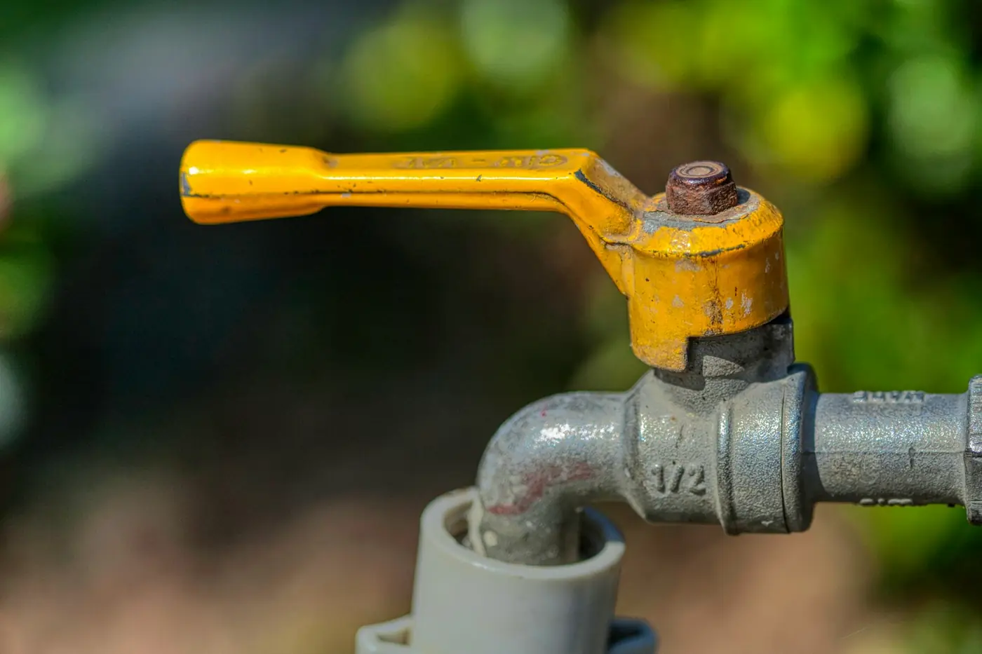 Lever-style ball valve with a yellow handle on a water pipe